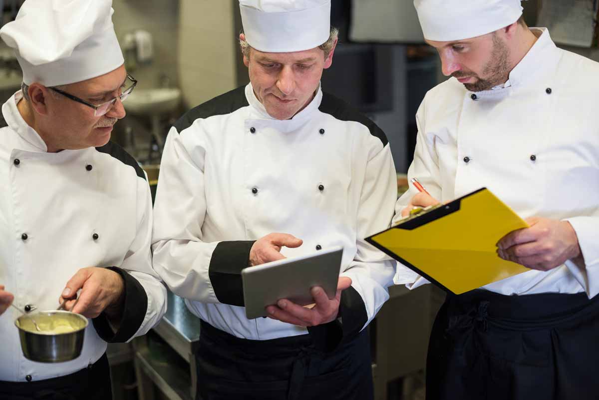 3 chefs de cozinha olhando para tablet