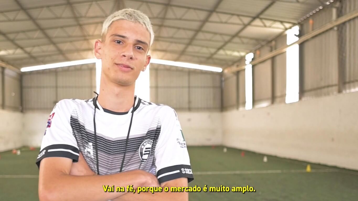 Capa do vídeo com um aluno de Educação Física de braços cruzados numa quadra da EnsinE.
