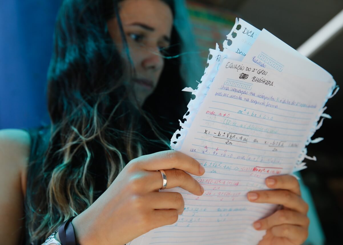 Jovem mulher estudante estuda folhas de anotações com fórmulas matemáticas